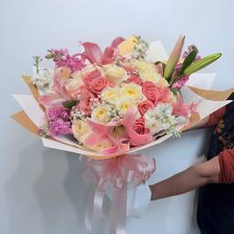 Pink and cream bouquet of roses and lilies wrapped with a ribbon