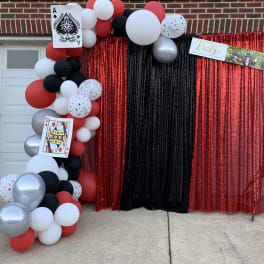 Red, black, white, and silver balloon arch with playing card decorations