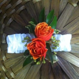 Two orange roses with greenery on a woven basket background