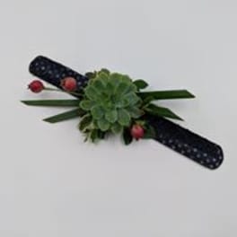 Green floral corsage with pink berries and dark ribbon