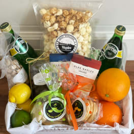 Gift basket with citrus fruit, popcorn, cookies, chocolate, and sparkling drinks
