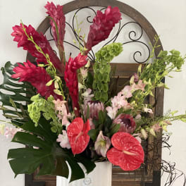 Tropical flower arrangement in a white vase with red and pink blooms