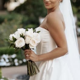 Bride holding a bouquet of white roses in a strapless gown