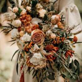 Large bouquet of peach and cream flowers with dark greenery