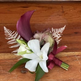 Small boutonniere with white and purple flowers tied with a burgundy ribbon