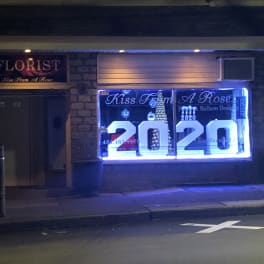 Florist storefront at night with a bright window display and large 2020 numbers