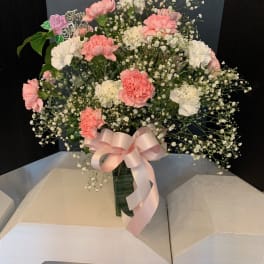 Pink and white carnations with baby's breath in a vase, tied with a pink ribbon