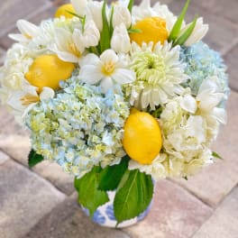 Bouquet of white flowers with lemons and pale blue blooms in a vase