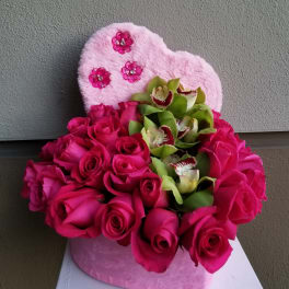 Pink roses and green orchids arranged in a heart-shaped plush box