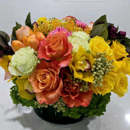 Colorful bouquet of roses, tulips, and orchids in a black vase