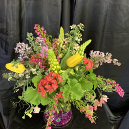 Colorful mixed floral arrangement in a clear vase with yellow tulips