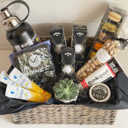 Gift basket with sports items, snacks, and a small succulent in a woven basket