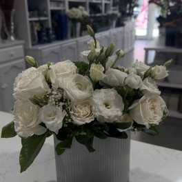 White roses and lisianthus arranged in a ribbed glass vase.