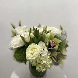 White and pale green floral arrangement in a glass vase