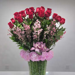 Red roses and pink flowers arranged in a clear glass vase