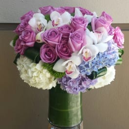 Pink roses and white orchids arranged with hydrangeas in a glass vase