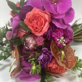 Bright bouquet with a coral rose, purple orchids, and orange anthuriums