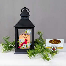 Black lantern with a lit candle and floral cardinal design