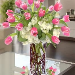 Pink tulips arranged with white hydrangeas in a clear glass vase