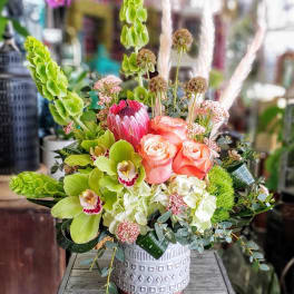 Mixed bouquet with pink roses, green orchids, and a decorative vase