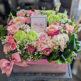 Pink and green rose arrangement in a gift box with a perfume bottle