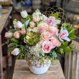 Pink roses and orchids in a decorative vase with greenery