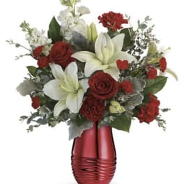 Red and white floral arrangement in a red vase