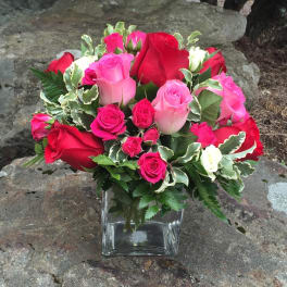 Pink and red roses arranged in a clear square vase