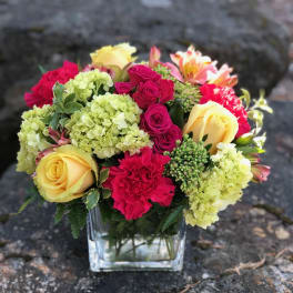 Mixed bouquet of roses, hydrangeas, and carnations in a glass vase