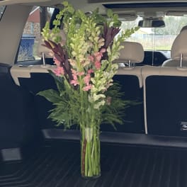 Tall mixed bouquet of pink and green flowers in a glass vase