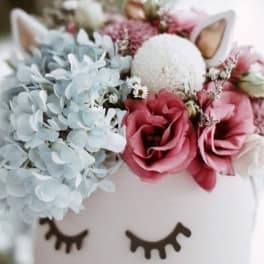 Floral arrangement in a white unicorn container with pink and blue blooms