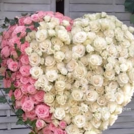 Heart-shaped arrangement of pink and white roses on a stand