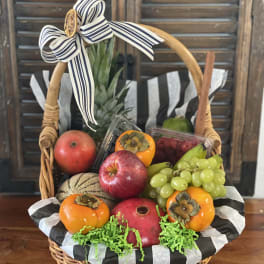 Fruit basket with apples, grapes, persimmons, and a ribbon bow