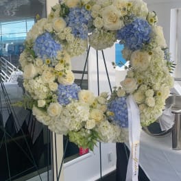 Large floral wreath of white and blue blooms on a stand