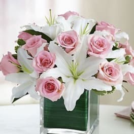 Pink roses and white lilies in a square glass vase