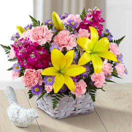 Basket arrangement of pink carnations, purple daisies, and yellow lilies