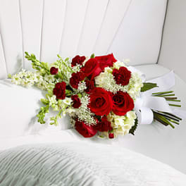 Red roses and white flowers arranged on a white chair