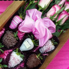 Box of pink roses with satin ribbon and chocolate-covered strawberries