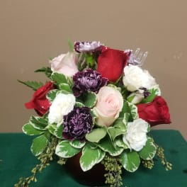 Mixed roses and purple carnations in a low round arrangement