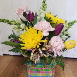 Colorful mixed flower arrangement in a plaid basket with a ribbon bow