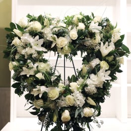 Heart-shaped standing wreath of white roses, lilies, and hydrangeas on a metal easel
