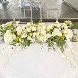 Long white floral table arrangement with roses and calla lilies