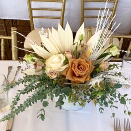 Low floral centerpiece with cream and tan roses on a white table