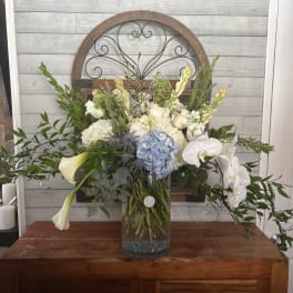 Large white and blue floral arrangement in a glass vase