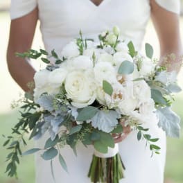 Bride holding a white bouquet with greenery