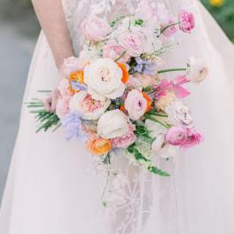 Bride holding a pastel bouquet of pink, white, and orange flowers