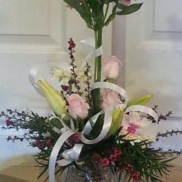 Tall mixed bouquet with pink lilies and roses in a glass vase