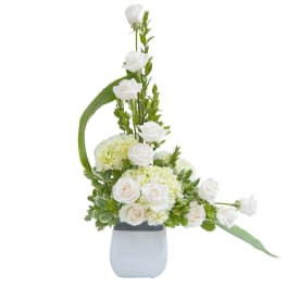 Tall white rose and hydrangea arrangement in a white square vase with an asymmetrical design