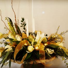 White floral centerpiece with gold ribbon and candles in a low container