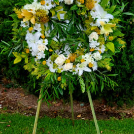 Circular standing wreath of white and yellow flowers on an easel